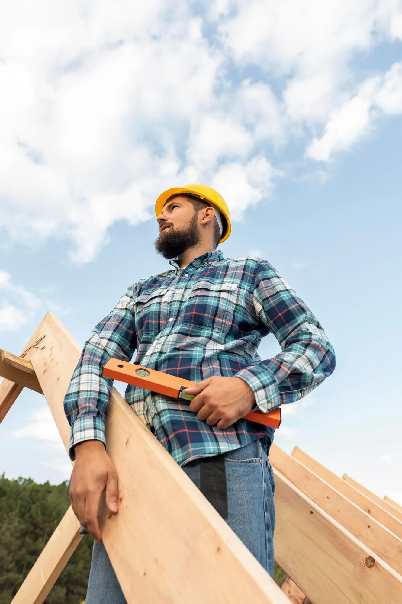 A worker using a level is building the roof of the house.